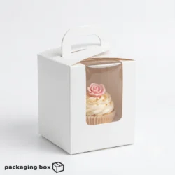 Single cupcake box with carry handle and clear front window holding a rose-decorated vanilla cupcake