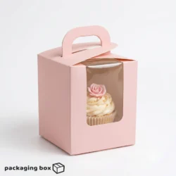 Single cupcake box with carry handle and clear front window holding a rose-decorated vanilla cupcake