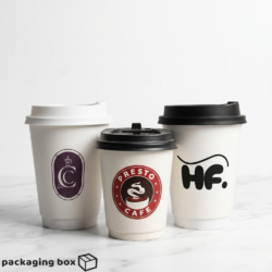 Three white 12oz custom screen printed coffee cups with brand logos and black and white lids on marble surface
