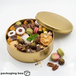 Golden round tin box filled with cookies, macarons and chocolates