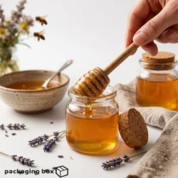 Hand holding a long handle wooden mixing stick dripping honey into a glass jar with cork lid, lavender flowers and bees in background